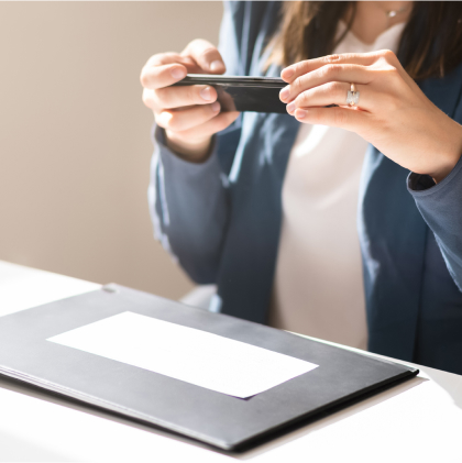 A woman holding a smartphone pointed at a bank check