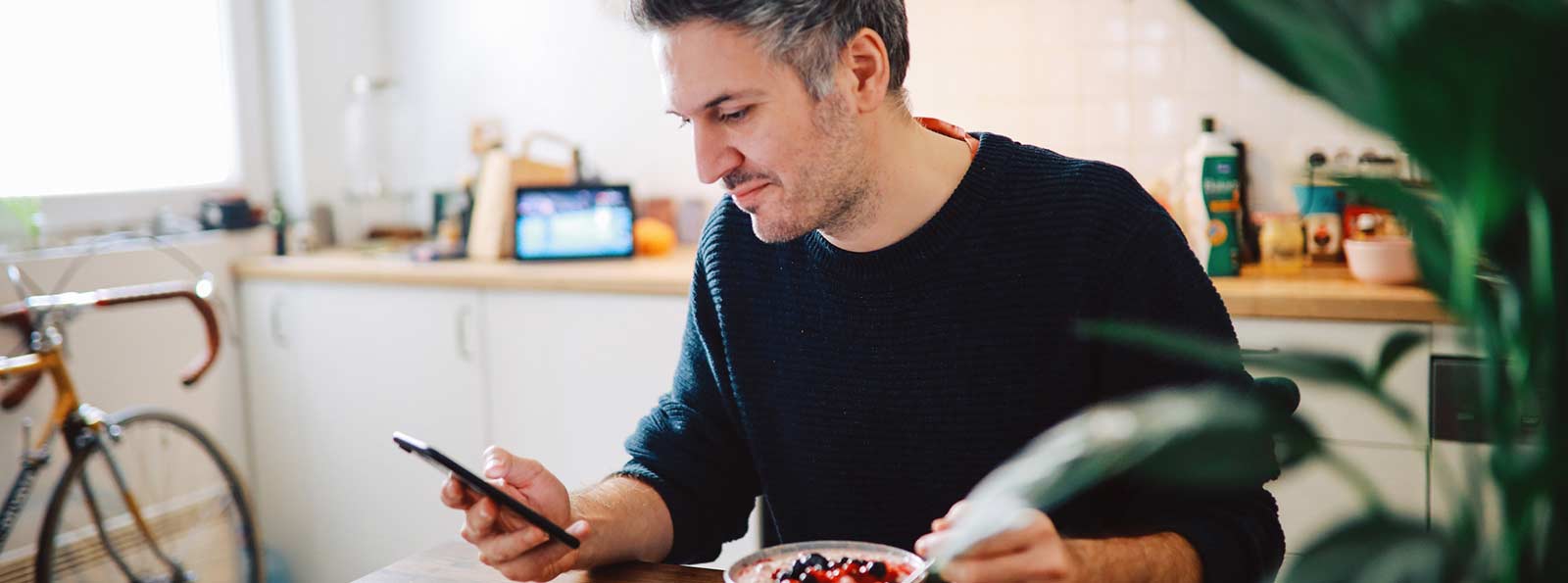 man eating cereal with cellphone